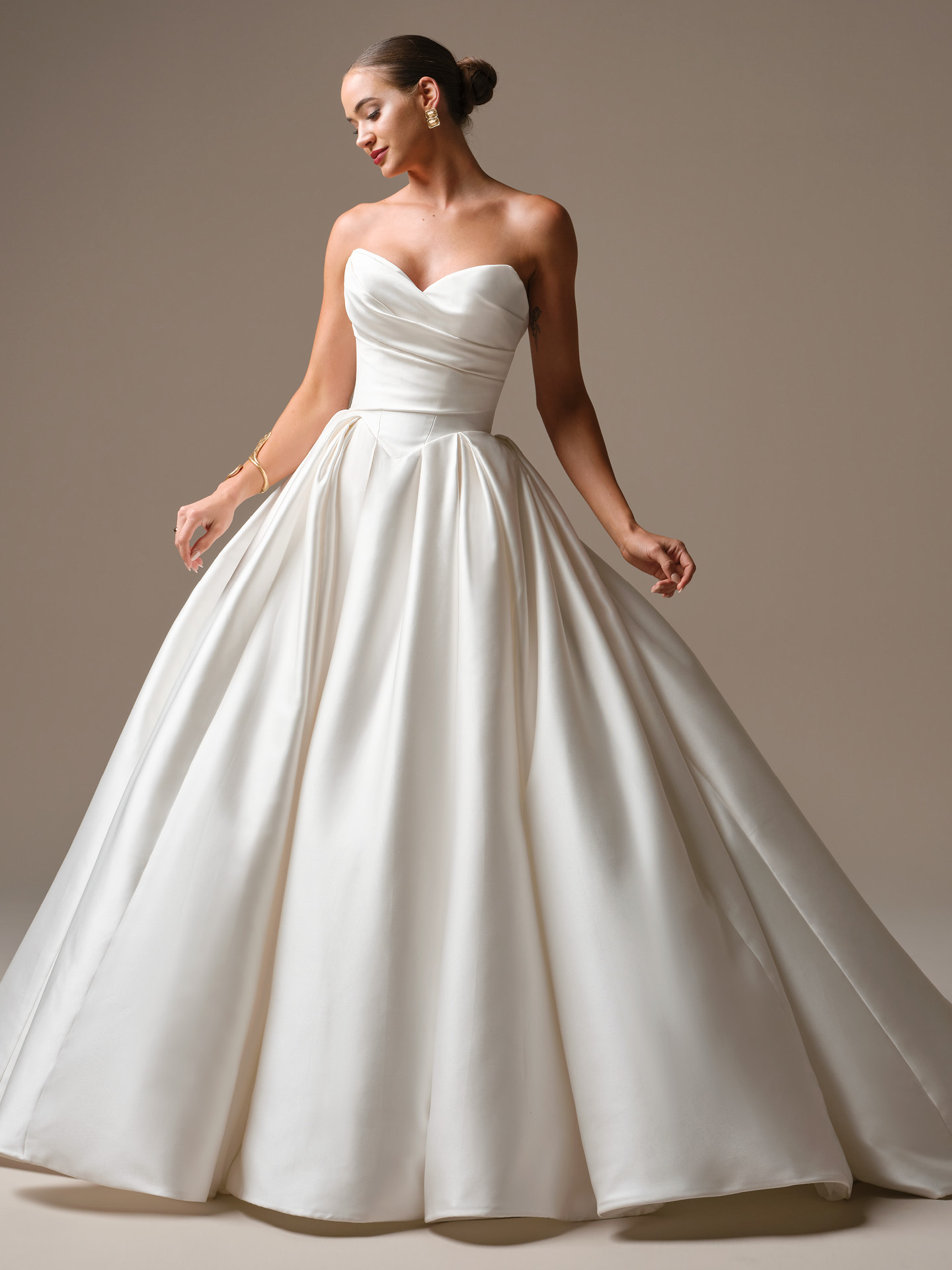 Elias satin ballgown wedding dress featuring a strapless sweetheart neckline, draped bodice, Basque waist, and full princess skirt in ivory satin.