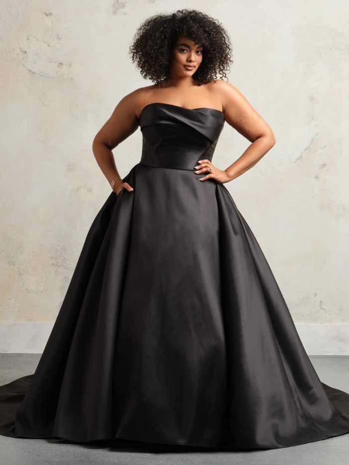 Bride wearing Faro by Sottero and Midgley, a strapless black satin ballgown wedding dress with asymmetrical draped bodice and full A-line skirt, designed for modern minimalism.