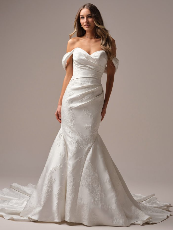 Full view of the Giselle Marie wedding gown featuring an off-the-shoulder fit-and-flare silhouette, ruched bodice, and luxe jacquard-inspired floral fabric with a chapel-length train.
