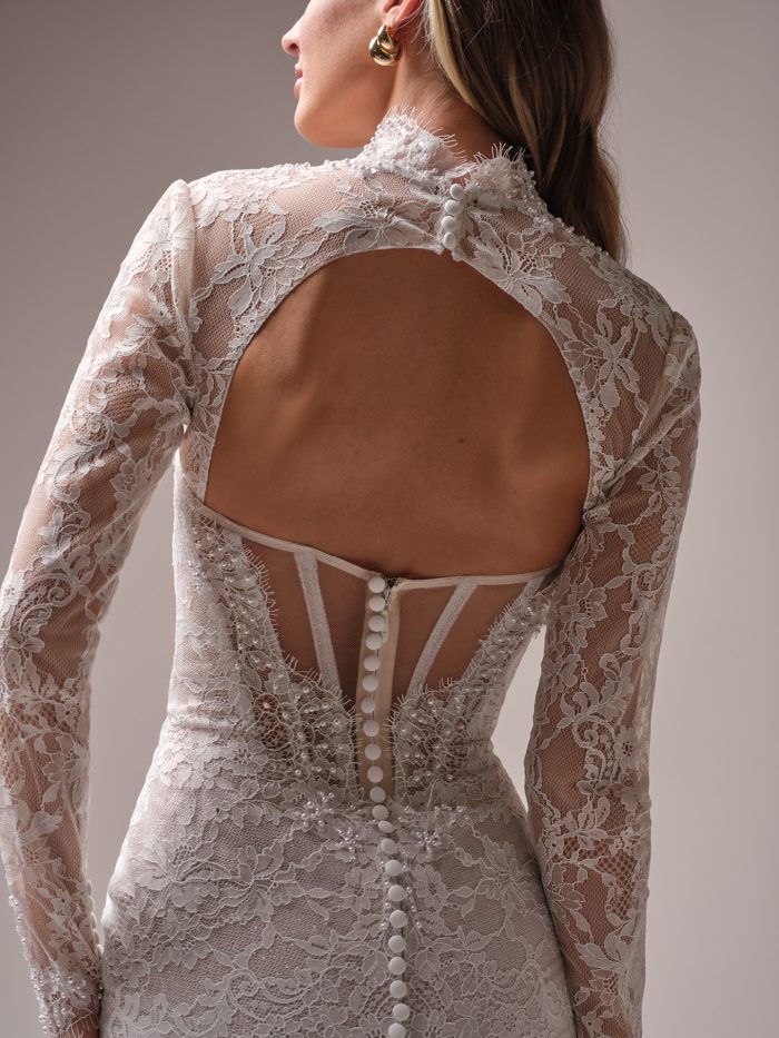 Back view of Sottero and Midgley Jovienne lace sheath wedding dress with open keyhole back, illusion detailing, and covered buttons trailing down the skirt.