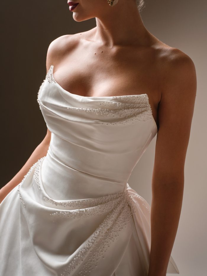Close-up of Sottero and Midgley Kincaid satin ballgown wedding dress featuring strapless draped bodice with pearl detailing