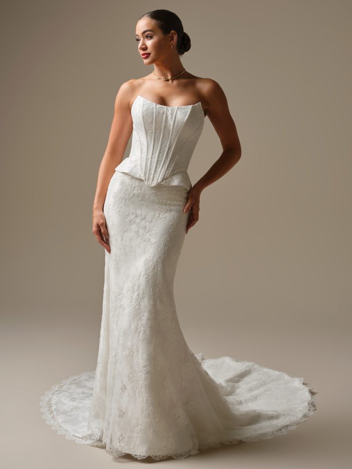 Lassen sheath wedding dress featuring unembellished allover Chantilly lace over Elodie Mikado, a two piece bodice with corset boning and peplum accents, and a strapless cat eye neckline.