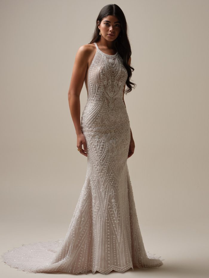 Bride wearing the Rhett sheath wedding dress featuring a high halter neckline, intricate beaded embroidery, and a fitted silhouette with a scalloped train.