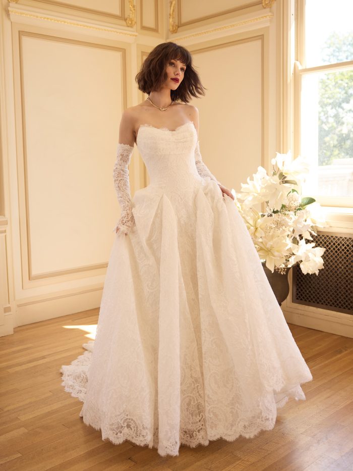 Tamar A-line wedding dress featuring a strapless lace bodice, off the shoulder lace sleeves, and a full textured lace skirt styled in an elegant ballroom setting.