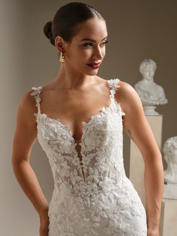 Close-up of the West wedding dress highlighting the illusion V-neckline, delicate beaded lace appliqués, floral straps, and fitted bodice details.