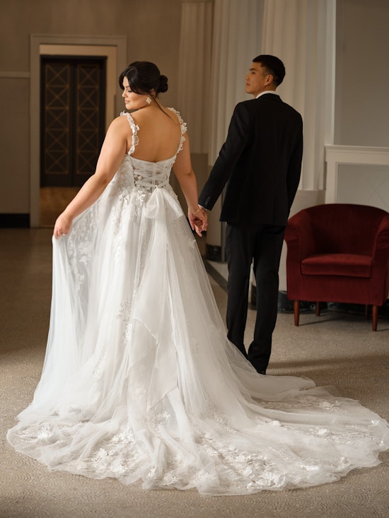 Bride holding groom's hand walking away together in a floral wedding dress with a lace up corset