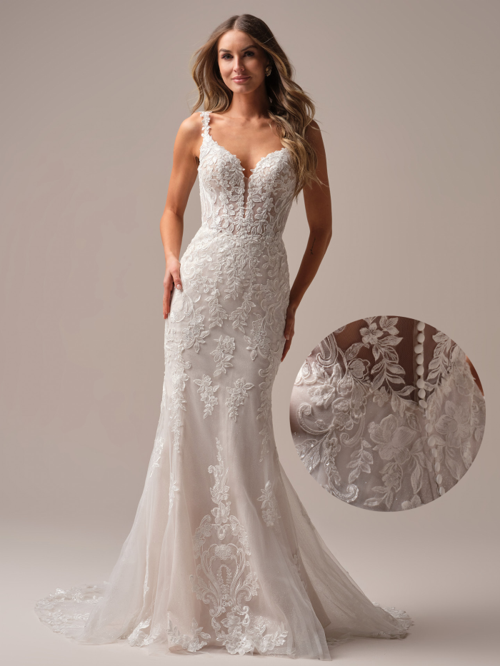 Bride wearing the Candice by Rebecca Ingram, a lace sheath wedding dress with a plunging V-neckline, delicate lace straps, floral lace appliqués throughout, and a soft tulle skirt, photographed in a neutral studio setting.